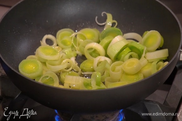 Разогреть в сковороде вок оливковое масло и обжарить лук-порей до прозрачности.