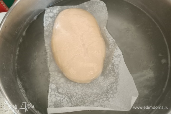 В кипящую воду добавить соду. Опустить тесто вместе с бумагой. Варить 30 секунд с каждой стороны.