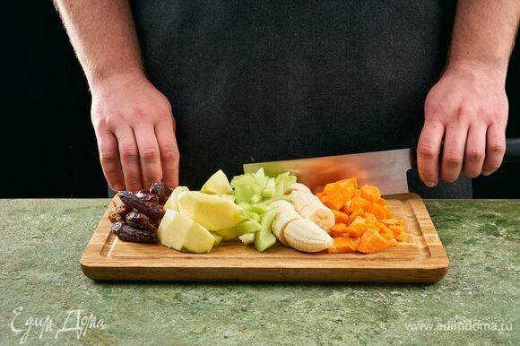 Морковь и яблоки помойте, снимите кожуру. Банан очистите. Нарежьте все на небольшие дольки. Стебли сельдерея помойте и тоже нарежьте небольшими дольками. Из фиников удалите косточки.