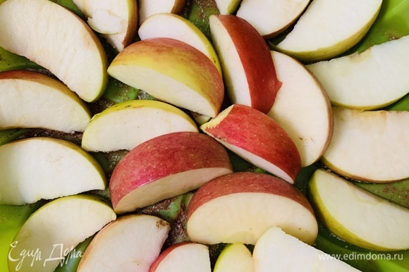 Выкладываем на сахар половину из нарезанных на дольки яблок.