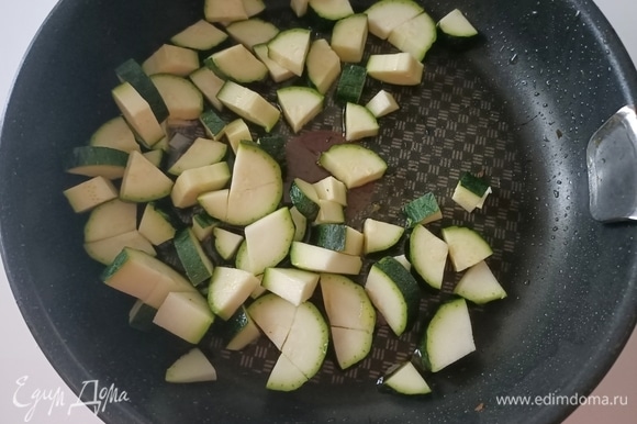 В сковороду налить оливковое масло, добавить чеснок и нарезанный цукини. Посолить, поперчить и жарить 5–7 минут до готовности.