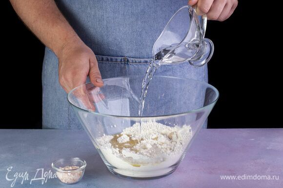 Добавьте воду и щепотку соли. Вымешивайте тесто, пока оно не станет однородным и эластичным. Скатайте тесто в шар и уберите в теплое место на 40 минут для подъема.