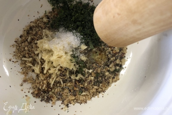 Переложите орехи в кастрюлю. Подавите или натрите мелко чеснок, нарежьте укроп, добавьте неполную чайную ложку соли и 2 ст. л. оливкового масла, хорошо перетрите все скалкой.