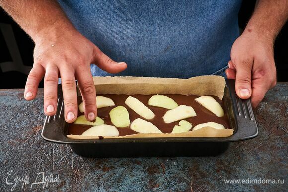 С яблока снимите кожуру и нарежьте дольками. Выложите их поверх теста. Запекайте в духовке при 180°C около 40 минут.