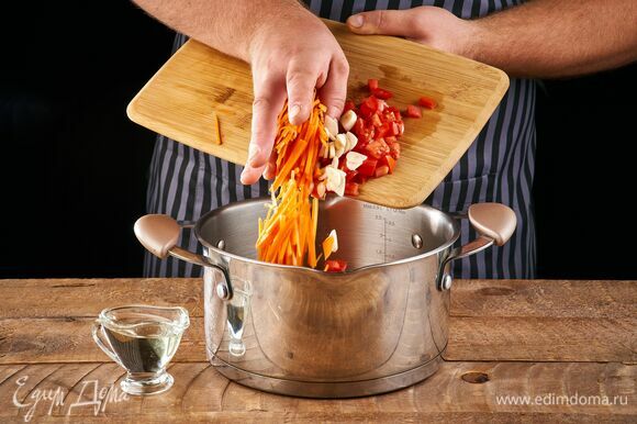 В кастрюлю налейте растительное масло, выложите морковь, чеснок, помидор. Жарьте на небольшом огне, пока морковь не станет мягкой.