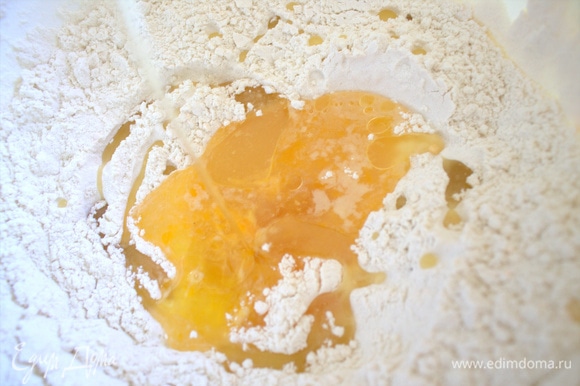В миску просеиваем муку, делаем ямку, вливаем яйцо с водой и солью и растительное масло.