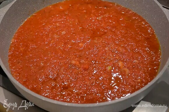 Приготовить томатный соус: разогреть в сковороде оливковое масло, выложить лук с чесноком, добавить перец чили и обжарить, добавить измельченные томаты в собственном соку и прогреть все на маленьком огне.