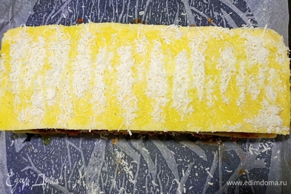 Затем начинку накрыть третьим слоем поленты, посыпать сыром, полить оливковым маслом и отправить противень с полентой запекаться в духовку при температуре 190°C на 15–20 минут.