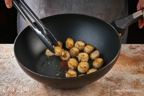 Обжарьте гребешки на раскаленной сковороде с добавлением оливкового масла по одной минуты с каждой стороны.