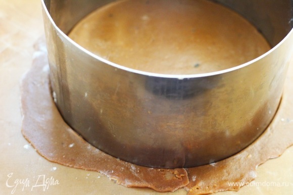Раскатать тесто толщиной 2–4 мм на пекарской бумаге и вырезать круг при помощи кольца диаметром 16 см. Мы выпекаем по два коржа на одном противне.