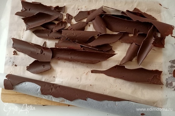 Достать шоколад из морозильной камеры. Аккуратно развернуть его. При разворачивании шоколад ломается и получаются интересные кусочки для декорирования тортика.