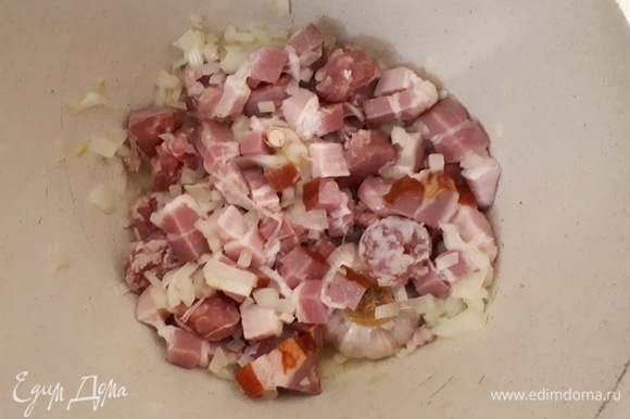 Нарежьте грудинку и колбаски на крупные кусочки и обжарьте вместе с луком.