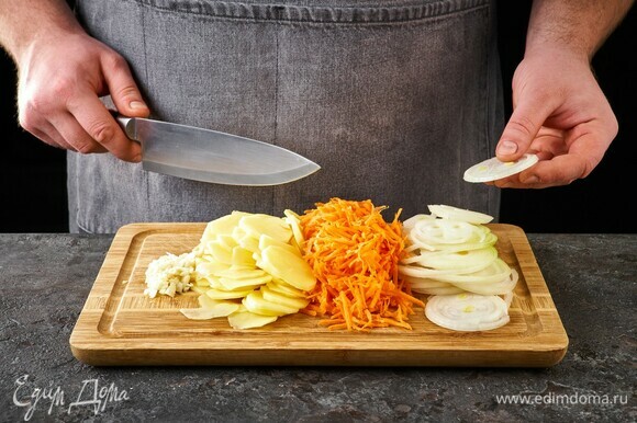 Картофель нарежьте тонкими кружочками. Морковь натрите на крупной терке, лук нарежьте тонкими кольцами, чеснок мелко порубите.