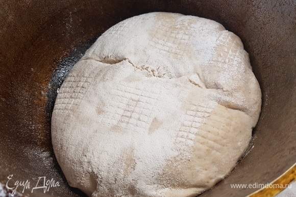 Выпекать хлеб надо в чугунке с крышкой. Для этого поставить чугунок в духовку, нагревать минут 30 при температуре 250°C. Как только чугунок нагрелся, быстро переложить хлеб, сделать надрез, накрыть крышкой и поставить выпекаться в духовку. Готовить 15 минут при 250°C, потом снизить до 200°C и выпекать еще 20 минут. Снять крышку и выпекать еще 5 минут.