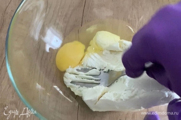 В миску выложите творог, разбейте яйцо и хорошо перемешайте.
