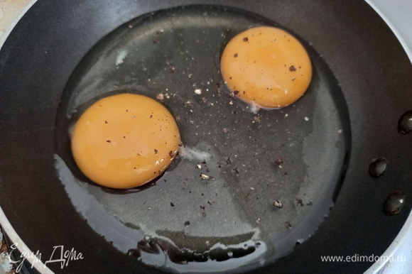 На сковороду наливаем подсолнечное масло, разбиваем яйца, солим и перчим. Мне было удобнее обжарить яйца порционно (по два в небольшой сковороде), но можно обжарить сразу все в одной большой.