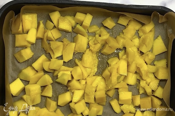 Выкладываем в форму или маленький противень, застеленный бумагой для выпечки. Распределяем кусочки манго, чтобы они легли равномерным слоем. Накрываем пищевой пленкой и убираем в морозилку на 3–4 часа или на ночь.
