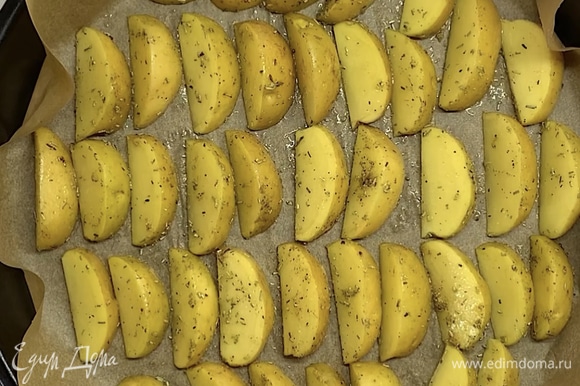 Выкладываем картофельные дольки на застеленный пергаментом противень. Ставим в заранее разогретую духовку на 20–25 минут при 180°C.