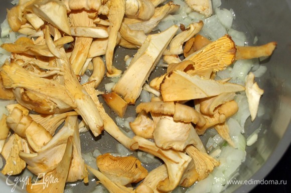 В глубокой сковороде на смеси растительного и сливочного масла обжарить лук и чеснок до мягкости лука. Добавить лисички и готовить 10 минут, изредка помешивая.