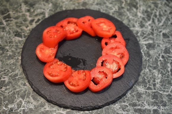 На тарелку для подачи выложите по кругу кружки помидоров.