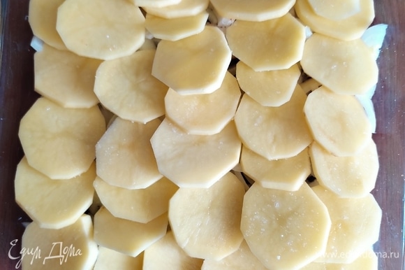 Очищенный картофель нарезать тонкими кружками и выложить на лук немного внахлест, чтобы картофель полностью закрыл луковый слой. Посолить, поперчить по вкусу.
