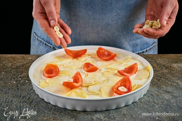 Сверху на картофель выложите помидоры и чеснок.