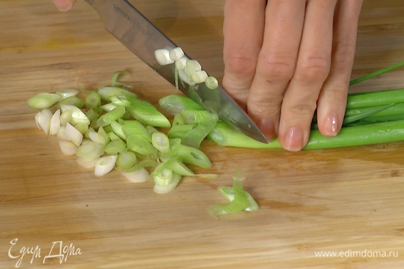 Зеленый лук нарезать, выложить к чесноку, добавить креветки и все обжарить.