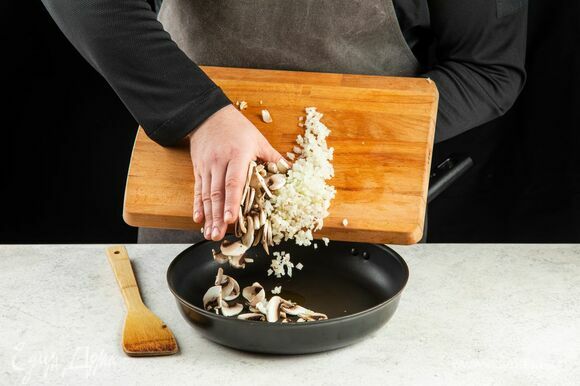 В сковороде разогрейте оливковое масло, выложите лук и грибы. Обжаривайте около 5 минут.