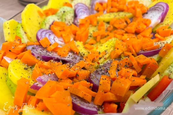 Почистите морковь и нарежьте мелким кубиком. Выложите морковь сверху по всей форме. Посолите, поперчите и добавьте сухого чеснока. Отправьте на 10 минут в предварительно разогретую до 180°C духовку.