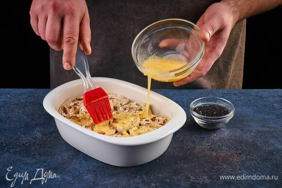 Яйцо взбейте вилкой. С помощью кулинарной кисти смажьте этой смесью рулет. Посыпьте сверху кунжутом и запекайте в разогретой до 200°С духовке около 20 минут.