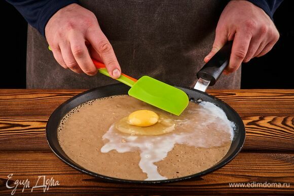 Разогрейте сковороду на среднем огне. С помощью половника выложите на сковороду тесто. Как только на нем появятся пузырьки, разбейте в центр яйцо. С помощью лопатки распределите белок по всей поверхности блина, но желток оставьте нетронутым.