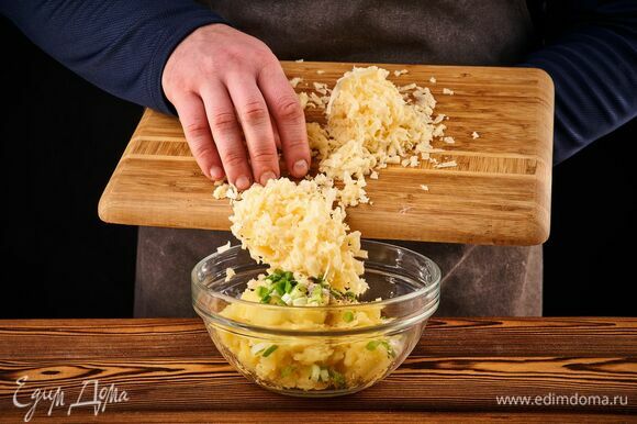 К пюрированному картофелю добавьте сметану, тертый сыр, мелко нарезанный зеленый лук, соль и перец. Перемешайте.
