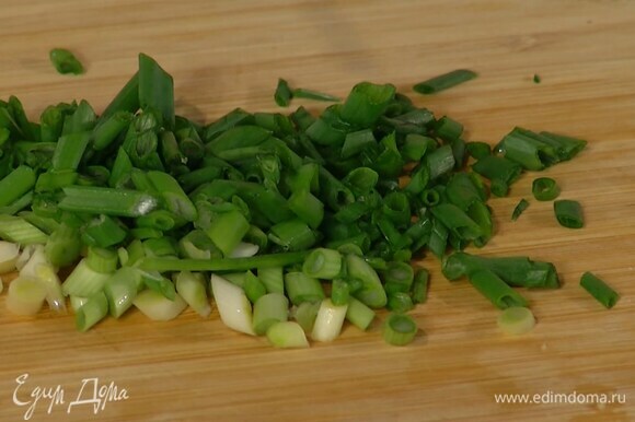 Зеленый лук тонко порезать наискосок и добавить в сковороду.