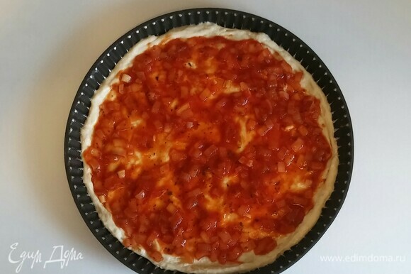 Противень для пиццы смазать оливковым маслом, чуть присыпать блинной мукой и раскатать тесто. Затем выложить на тесто томатный соус.