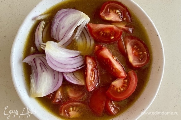 Нарезать остальные овощи: помидоры — небольшими ломтиками, красный лук — клиньями. Поместить их в соус и оставить на время, пока запекаются баклажаны.