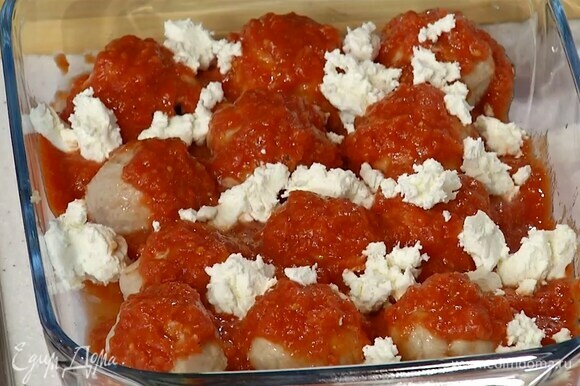 Полить фрикадельки томатным соусом, сверху разложить кусочки сливочного сыра и запекать в разогретой духовке 30–35 минут.
