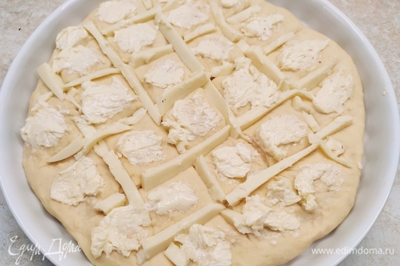 Для начинки смешайте мягкое сливочное масло с чесноком (натрите его на мелкой терке). Сыр нарежьте брусочками. На подошедшей лепешке сделайте надрезы в виде решетки. В надрезы поместите сыр, а квадратики смажьте чесночным маслом.