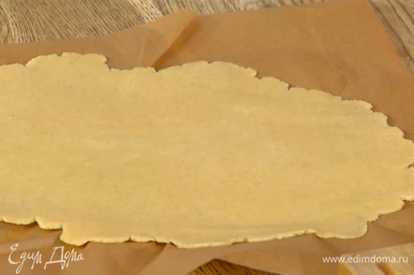 Вымесить тесто руками и сформировать из него шар, затем поместить между двумя листами бумаги для выпечки и раскатать в пласт толщиной 2–3 мм.