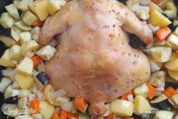 Когда курица будет наполовину готова, достать форму из духовки. Выложить в нее овощи и поставить снова в духовой шкаф. Продолжать запекать до готовности всех ингредиентов.