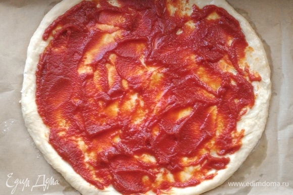 Смазать основу для пиццы томатным соусом, оставляя бортики 1–1,5 см.