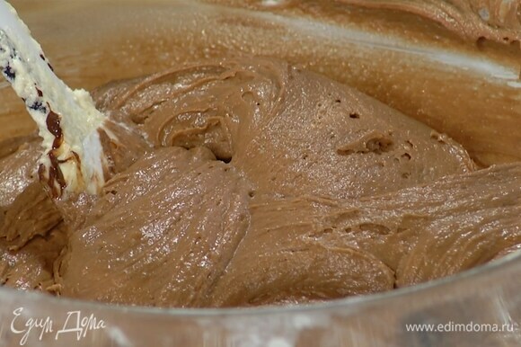Яично-сливочную массу переложить в глубокую миску, добавить сметану, ванильный экстракт, всыпать муку с разрыхлителем и вымешать тесто лопаткой, затем влить растопленный шоколад и еще раз вымешать.