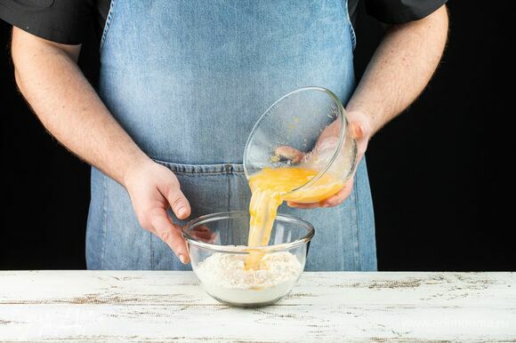 Влейте к сухим ингредиентам яичную смесь и замешайте тесто. Удобнее вливать жидкость в несколько этапов.