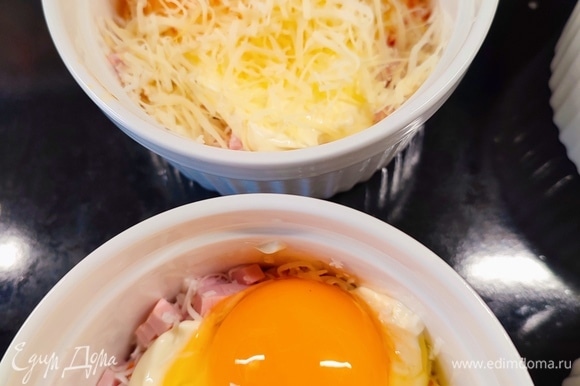 В каждую формочку сверху разбить по яйцу и посыпать сверху тертым сыром.