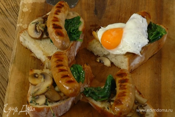 На обжаренный хлеб выложить грибы с чесноком, шпинат, колбаски и поджаренные яйца.