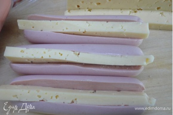 Сосиски разрезать вдоль и в разрезы вложить кусочки сыра.