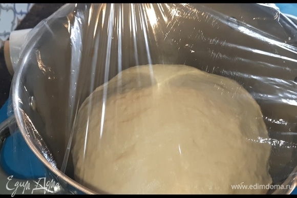 Переложите тесто в очень глубокую емкость, накройте пленкой без отверстий. Сверху укутайте чем-нибудь теплым и оставьте в теплом месте подниматься на 1,5 часа.