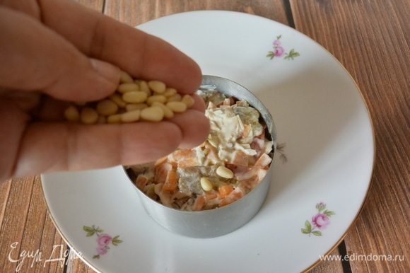 Посыпать салат кедровыми орешками.