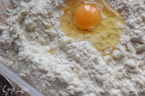 В центр массы добавить яйцо, которое до этого момента находилось в холодильнике. Добавить ледяную воду. Перемешать, долго не перемешивать, чтобы тесто меньше соприкасалось с теплыми руками.