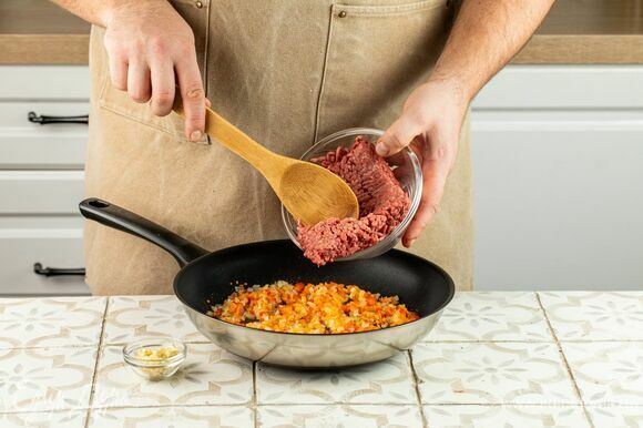Добавьте к овощам фарш и обжарьте до готовности, помешивая и разбивая лопаткой на кусочки. Добавьте измельченный чеснок.