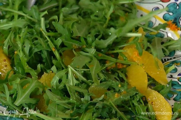 Руколу и мякоть апельсина выложить в салатник, посыпать цедрой, полить половиной заправки и все перемешать.